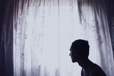 Man looking at curtain hanging on window