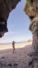 Full length of man on rock at beach against sky