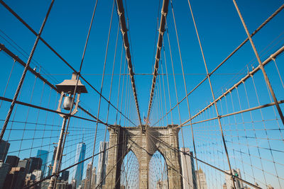 Low angle view of brooklyn bridge in city against clear blue sky