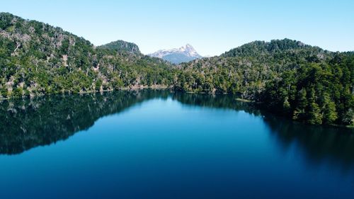 Scenic view of lake and mountains against clear blue sky