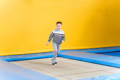 Portrait of boy standing against yellow wall