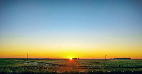 Scenic view of field against clear sky during sunset
