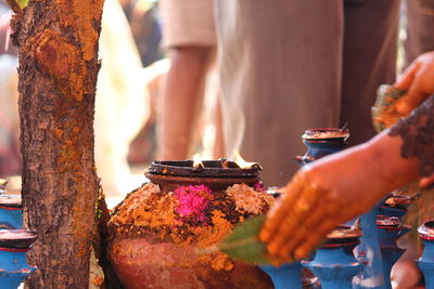 Close-up of hands by earthen pot at temple