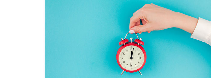 Close-up of woman with alarm clock against blue background