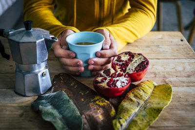 Midsection of woman wearing sweater holding bowl