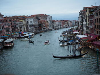 Boats moored in canal amidst buildings in city