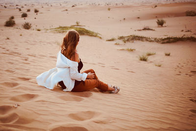 Woman sit back at desert sand