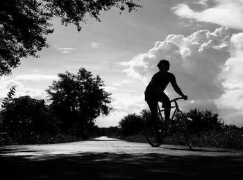 Man cycling on road against sky