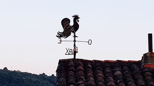 Low angle view of weather vane against clear sky