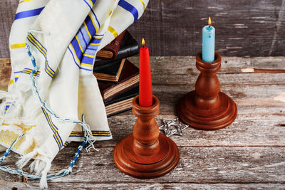 High angle view of burning candles with books and scarf on table