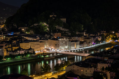 High angle view of illuminated city by river at night