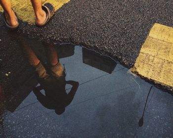 Low section of man standing on puddle