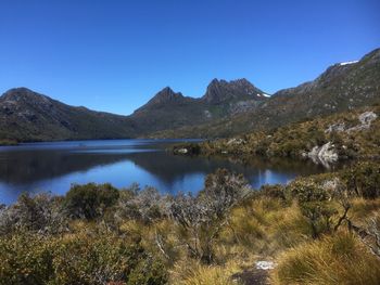 Scenic view of lake and mountains against clear blue sky