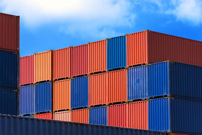 Stack of multi colored cargo container at harbor against blue sky