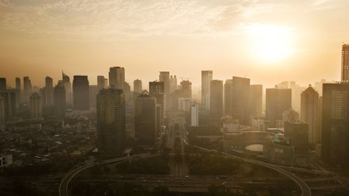 Modern buildings in city against sky during sunset