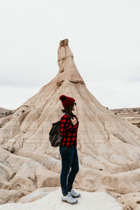 Woman standing on rock against sky