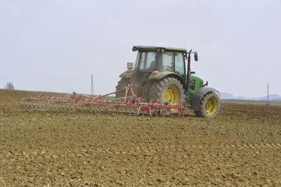 Tractor on agricultural field against sky