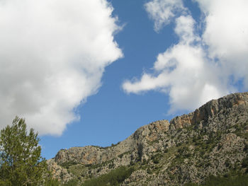 Big mountain surrounded by pine trees with blue sky. bright blue sky with white clouds