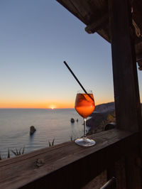 Red wine on table against sea during sunset