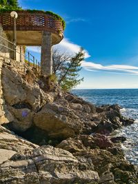 Scenic view of rocks by sea against sky