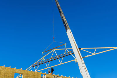 Low angle view of crane against blue sky