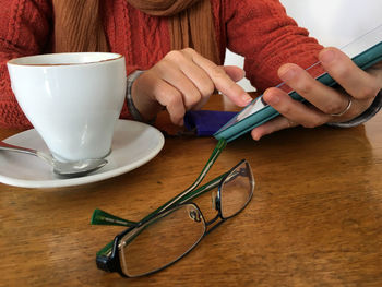 Midsection of woman sitting by coffee using digital tablet