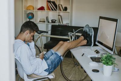 Teenager or young man student on the desktop with the mobile phone and computer