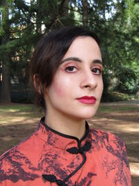 Close-up portrait of young woman against trees