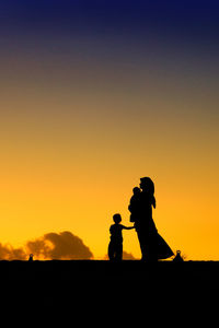 Silhouette of woman with children at sunset