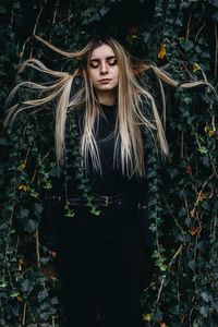 Young woman against plant