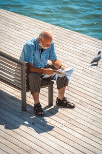 Full length of man reading newspaper on pier