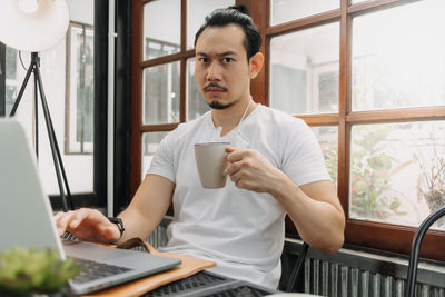 Young man using mobile phone while sitting on table