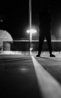 Rear view of people walking on illuminated street at night