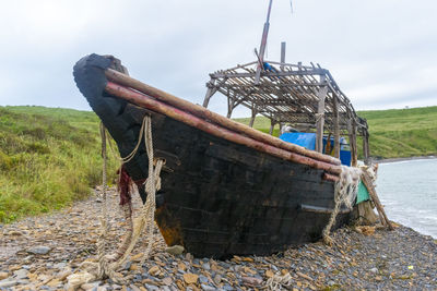 Abandoned boat moored on beach against sky