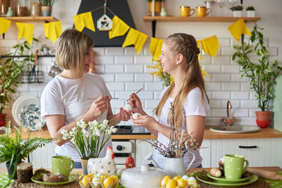 Mother and daughter painting eggs at kitchen