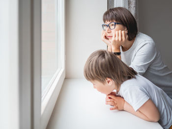 Sad woman looks at the window. forced stay at home. mother and son. mom and child.