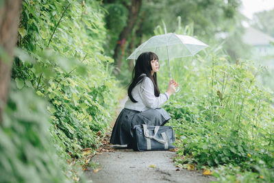 Side view of woman sitting in rain
