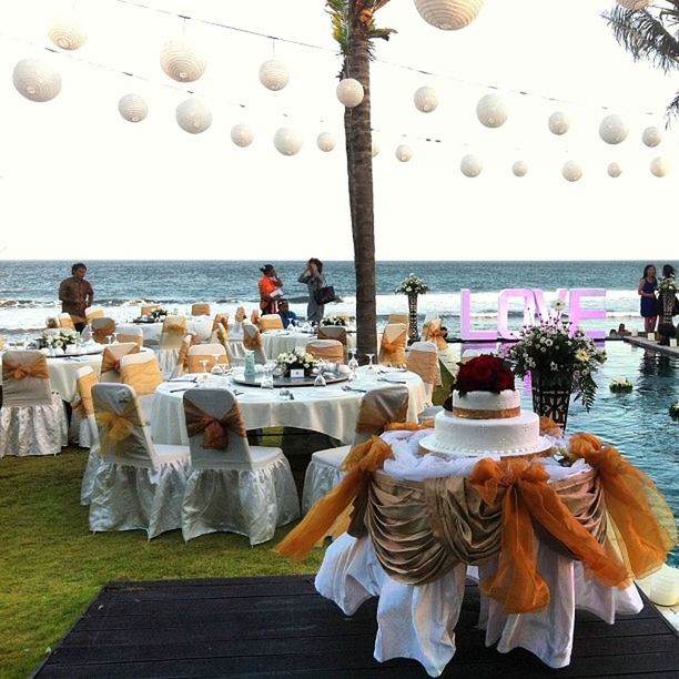 table, sea, chair, water, arrangement, sky, in a row, restaurant, parasol, large group of objects, horizon over water, decoration, beach, group of objects, sunshade, beach umbrella, day, hanging, variation, sunlight