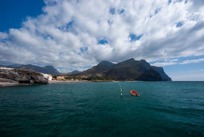 Scenic view of sea and mountains against sky