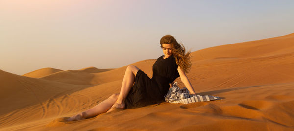 Young woman in desert against sky