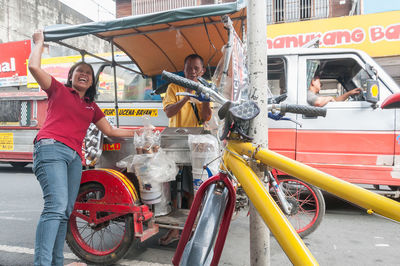 Full length of young woman with bicycle in city