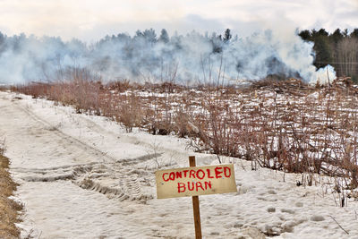 Controlled burn sign with active burn on a farm property in simcoe country ontario canada