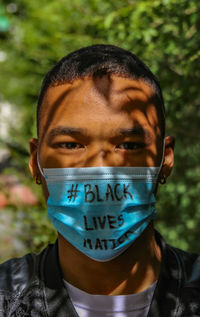 Portrait of man wearing mask with text while standing outdoors