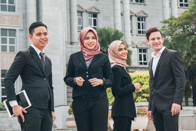 Happy friends standing by building in city