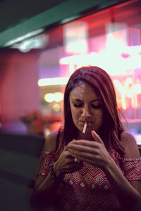Portrait of young woman smoking outdoors