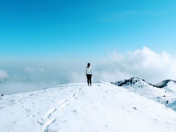 Rear view of man standing on snow against sky