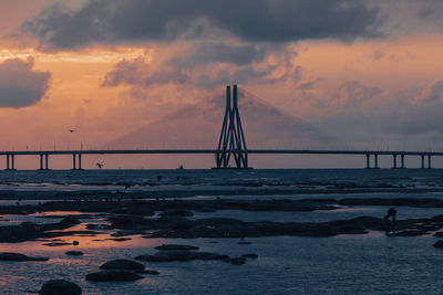 Bridge over sea against sky during sunset