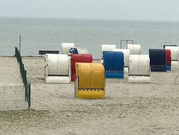 Deck chairs on beach against sky