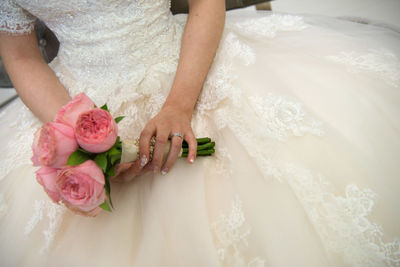 Midsection of bride holding pink flowers bouquet during wedding ceremony