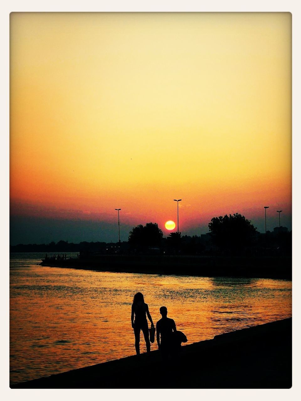 sunset, silhouette, water, men, orange color, transfer print, lifestyles, leisure activity, togetherness, sky, copy space, auto post production filter, person, standing, bonding, nature, sea, scenics